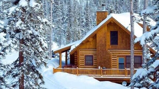 A wooden cabin surrounded by snow-covered trees and mountains. - Fish Creek House Bed & Breakfast (Whitehall)