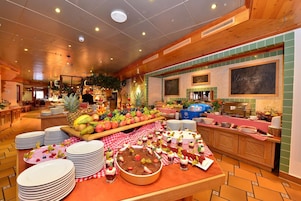 Un'area buffet con frutta, dolci e un angolo caffè in un ristorante.