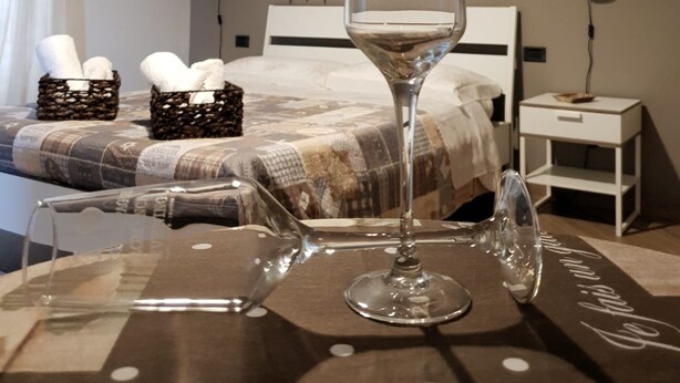 A neatly made bed with a patterned bedspread, a bedside table with a lamp, and a glass with a romantic inscription. - B&B Tre Passi Dalla Torre (Montesarchio)