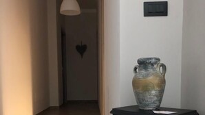 A room with a black wood-burning stove, a large vase on top, and a heart-shaped decoration on the wall. - B&B Tre Passi Dalla Torre (Montesarchio)