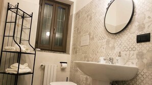 A bathroom with a toilet, a sink, a towel rack, and a window. - B&B Tre Passi Dalla Torre (Montesarchio)