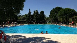 A swimming pool surrounded by trees and a sandy area. - H La Cabaña (Pozuelo de Alarcon)