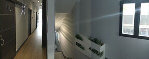 A modern hallway with a wooden floor, a white wall with built-in planters, and a window with blinds. - H La Cabaña (Pozuelo de Alarcon)