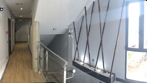 A corridor with a glass railing, a wooden floor, and a window with a view of greenery outside. - H La Cabaña (Pozuelo de Alarcon)
