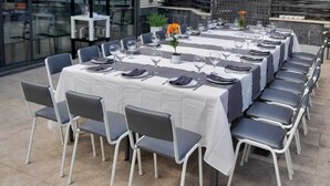 A long dining table set outdoors with chairs, a building in the background, and trees. - H La Cabaña (Pozuelo de Alarcon)