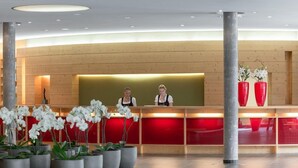 A reception area with a wooden reception desk, two staff members, and potted white orchids. - Aqua Dome Therme (Laengenfeld)