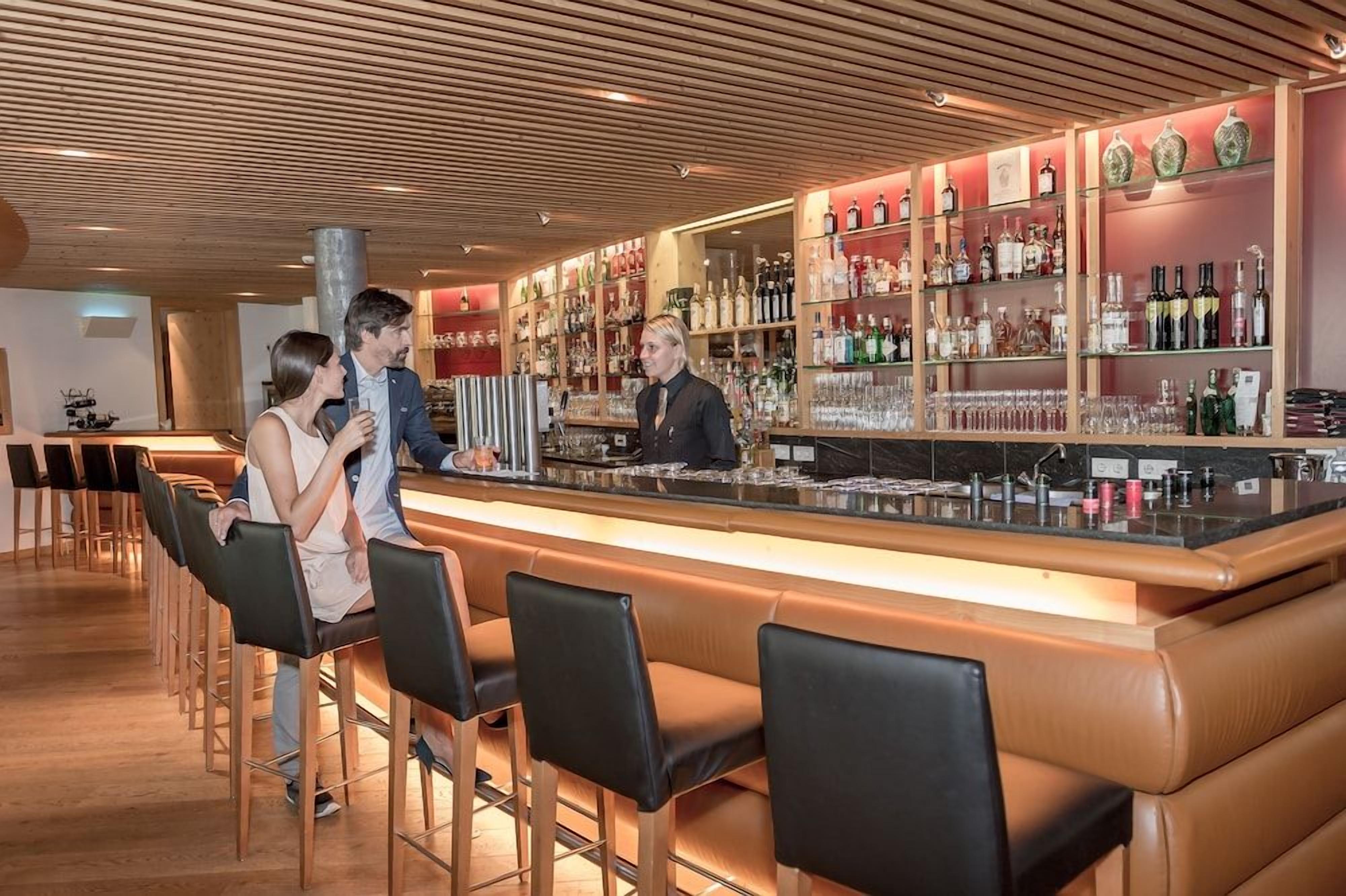 Eine Bar mit einer Theke, Barhocker und Regalen voller Flaschen.
