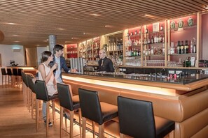 A bar area with a counter, bar stools, and shelves of bottles. - Aqua Dome Therme (Laengenfeld)