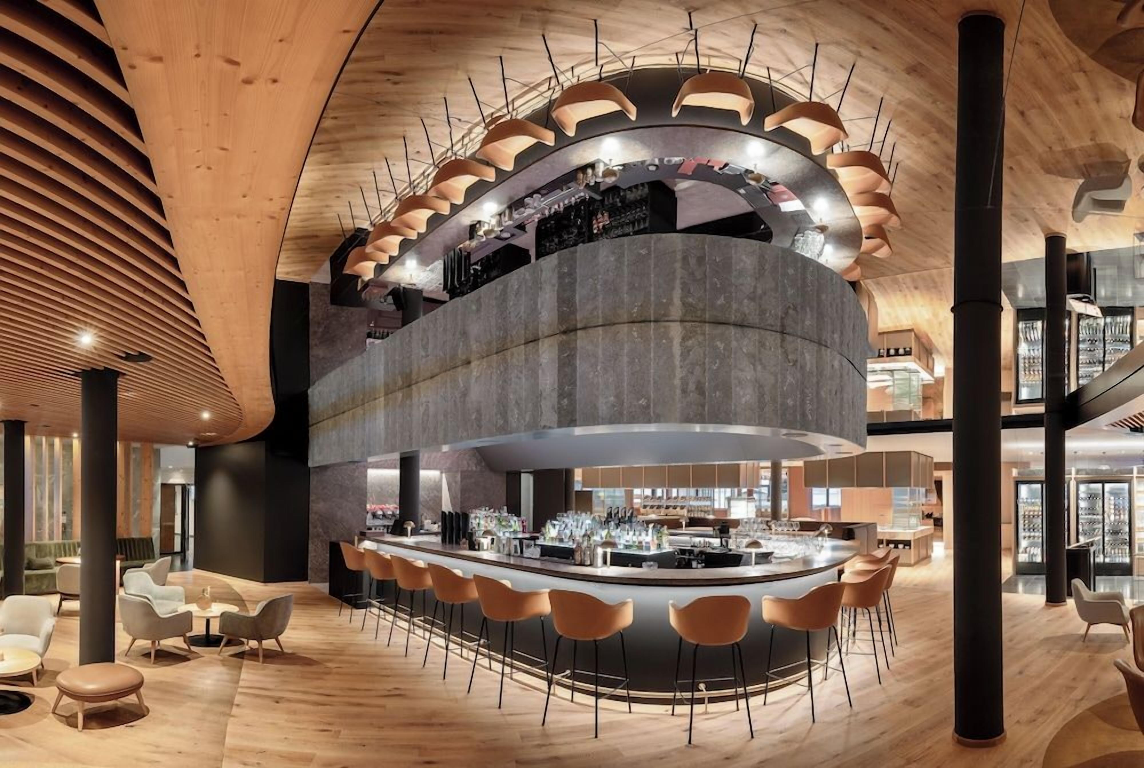 Eine moderne Bar mit einer gebogenen Theke, Sitzgelegenheiten und einem außergewöhnlichen Deckenstil.