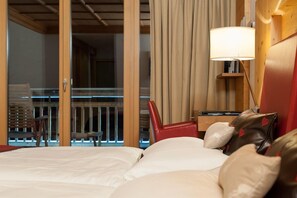 A hotel room with a bed, a red chair, a lamp, and a view of a balcony with lights. - Aqua Dome Therme (Laengenfeld)