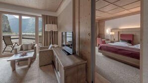 A hotel room with a bed, a desk, a chair, and a view of mountains through large windows. - Aqua Dome Therme (Laengenfeld)
