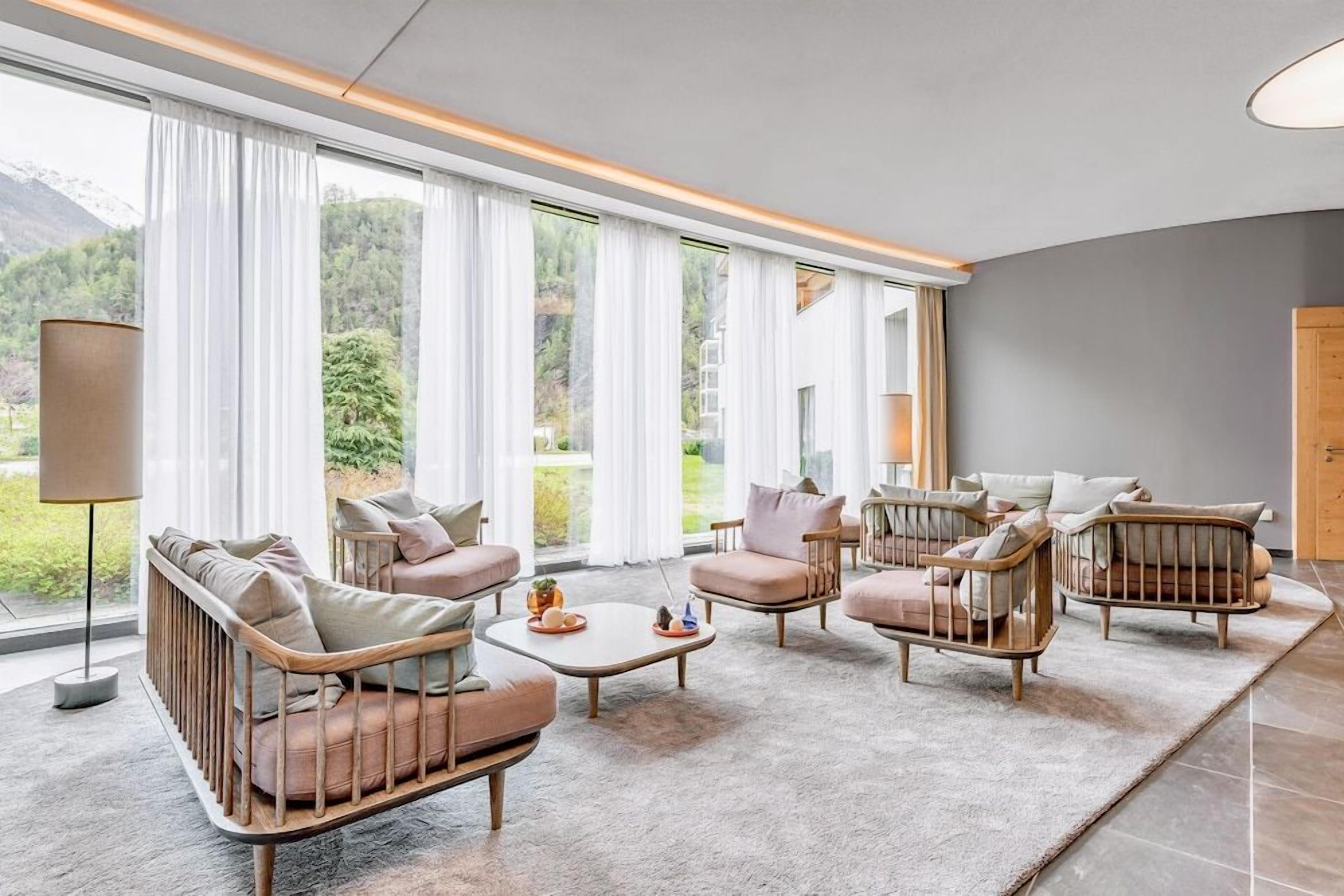Ein modernes Wohnzimmer mit großem Fenster, einer Sofagarnitur, einem Couchtisch und einer Lampe.
