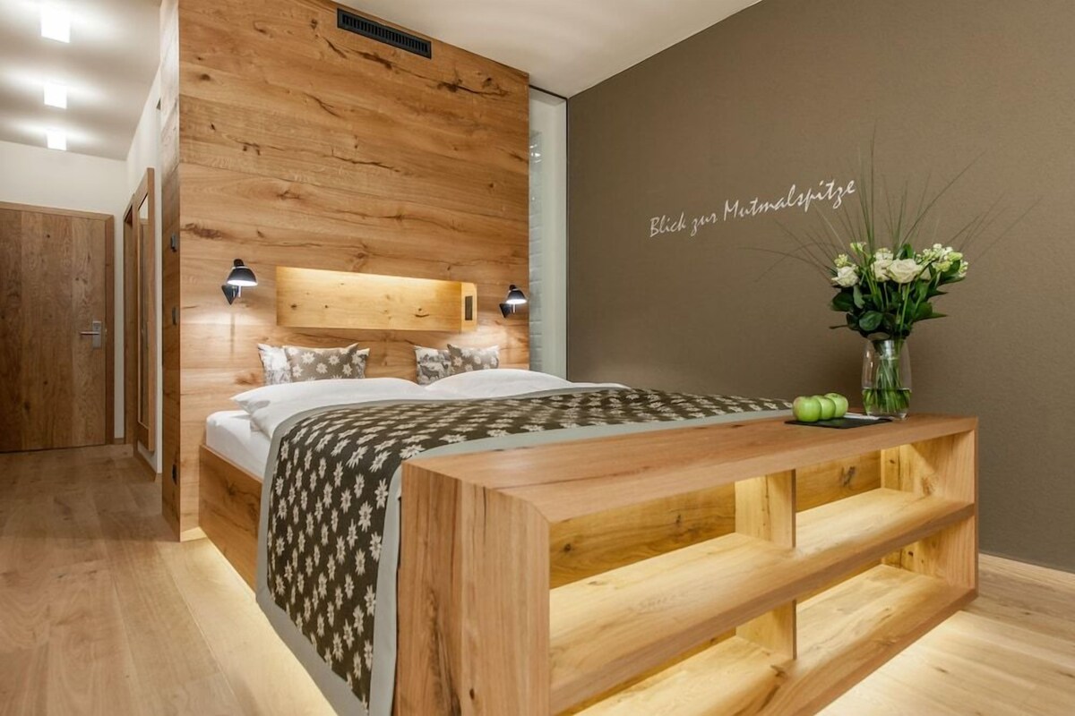 A bedroom with a wooden headboard, a bedside table with a vase of flowers, and a wall with a sign.