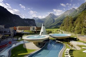 Un resort con piscina, dos fuentes y montañas al fondo.