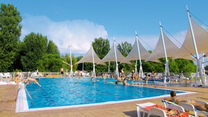 A swimming pool with multiple people swimming and sunbathing. There are white umbrellas providing shade over the pool area. - Happy Camp mobile homes in Füred Camping (Balatonfured)