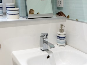 A modern bathroom with a white sink, chrome faucet, and a soap dispenser. - Sandpipers Loft (North Berwick)
