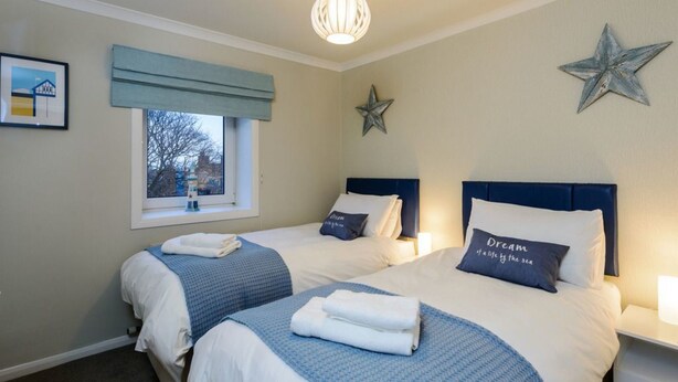 Habitació d'hotel amb dos llits, una finestra amb vista, una decoració amb estrelles i un quadre al mur.