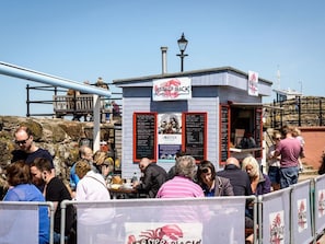 A lobster shack with a menu board and a small outdoor seating area. - Sandpipers Loft (North Berwick)
