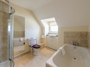 A modern bathroom with a glass shower enclosure, a freestanding bathtub, and a toilet with a wooden seat. - Green Craig (Aberlady)