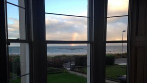 A view from a window overlooking a grassy area and the sea, with a rainbow visible in the distance. - Tensea -charming 3-bed Apartment in North Berwick (North Berwick)
