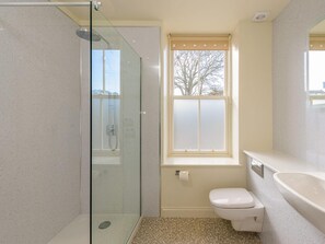 A bathroom with a glass-enclosed shower, a toilet, and a sink.