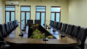 A conference room with a long table, black leather chairs, and microphones. - Dream Valley Park & Lodge (Lusaka)