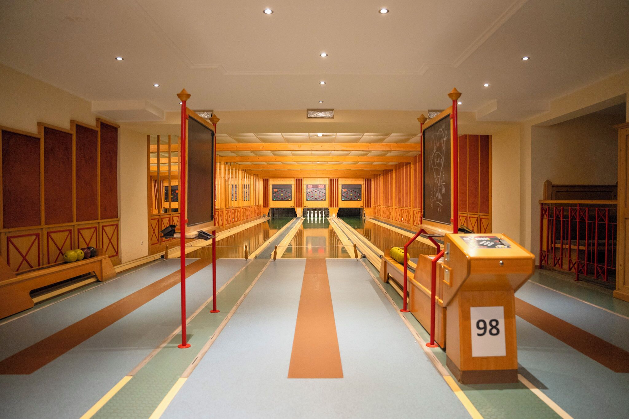 Un hall d’hôtel avec un couloir central, des lambris en bois et une enseigne portant le numéro 98.
