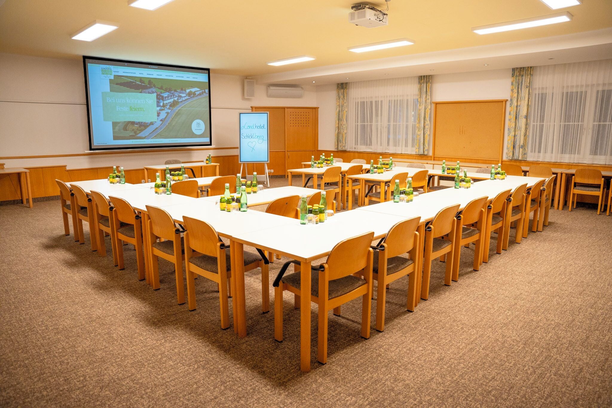 A conference room with a long table, chairs, and a projector screen displaying a presentation.