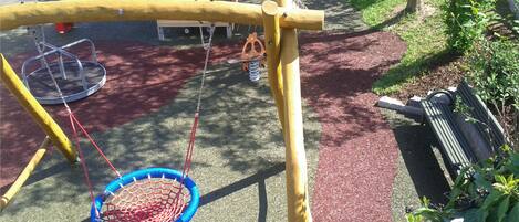 A playground with a swing set, a slide, and a wooden climbing structure.