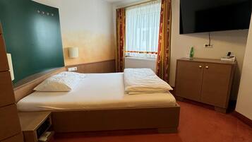Une chambre d’hôtel avec un lit, une télévision, un bureau et une fenêtre avec des rideaux.