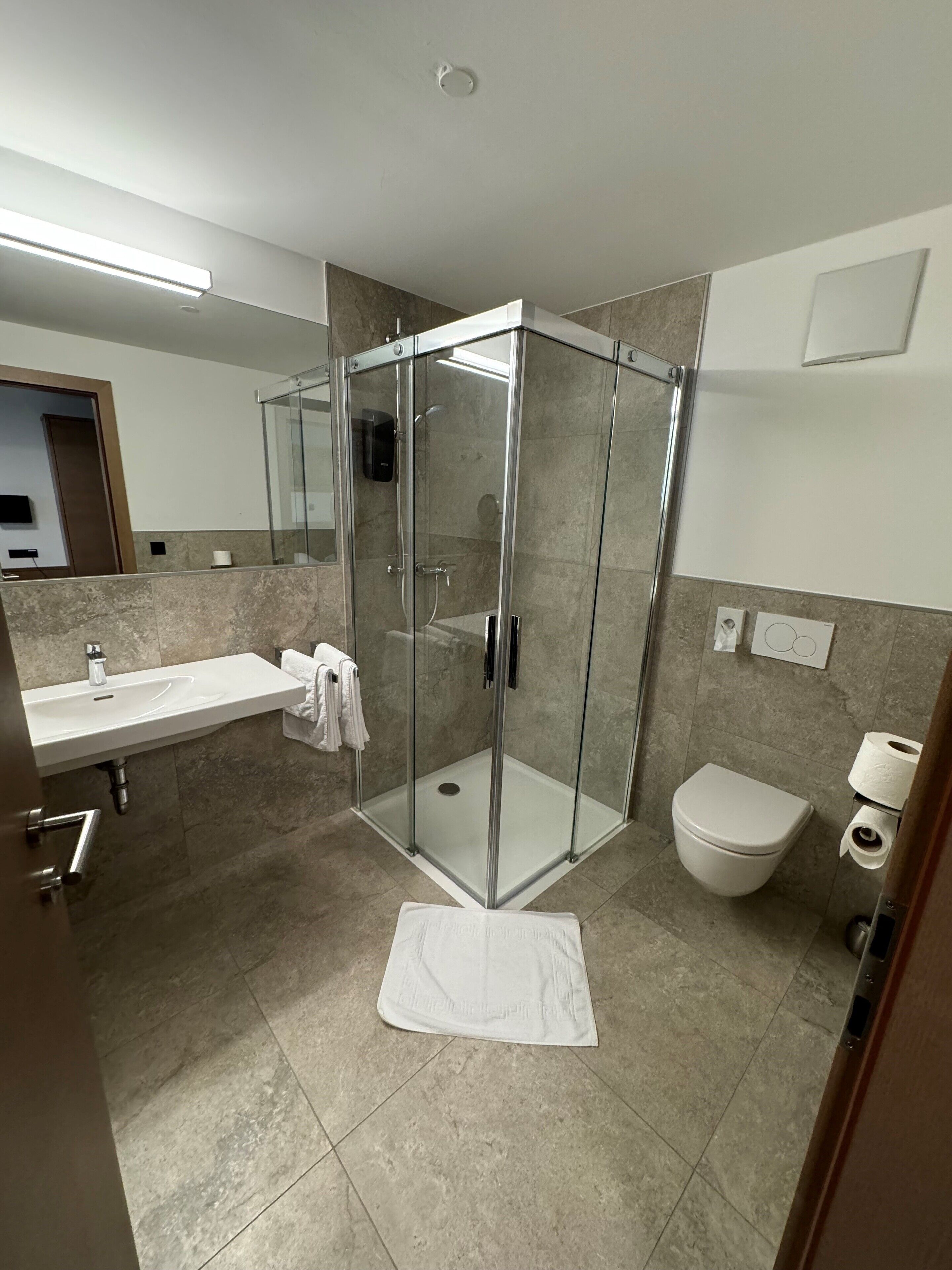 A modern bathroom with a glass-enclosed shower, a white sink, and a toilet.