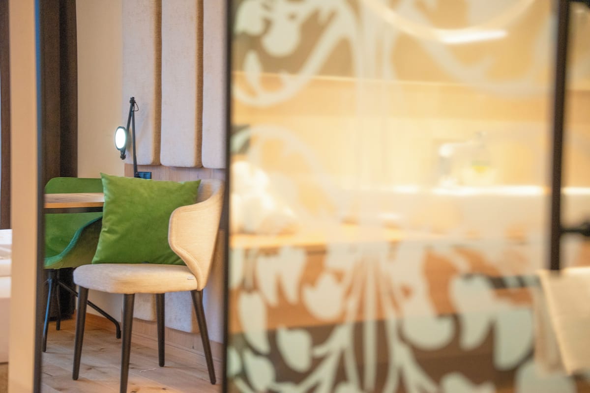 A dining area with a table and chairs, a lamp, and a patterned wall.