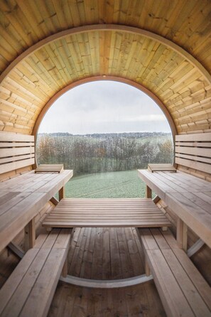 Una estructura de madera circular con bancos mirando hacia un campo cubierto de césped.