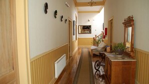 Um corredor com piso de madeira, um radiador, um banco, um armário de madeira com espelho e decorações nas paredes.