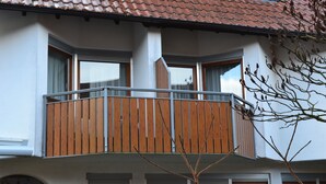 A multi-story building with a balcony on the second floor, large windows, and a tiled roof.