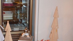 A room with a tiled floor, a white lantern, and two wooden Christmas trees.