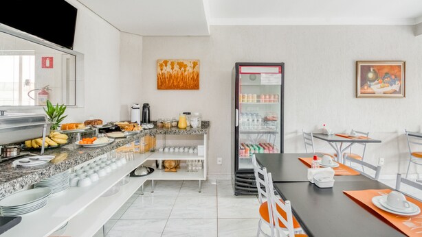 A modern hotel dining area with a buffet, seating arrangements, and a refrigerator. - Hotel Jardim Do Cedro (Cedral)