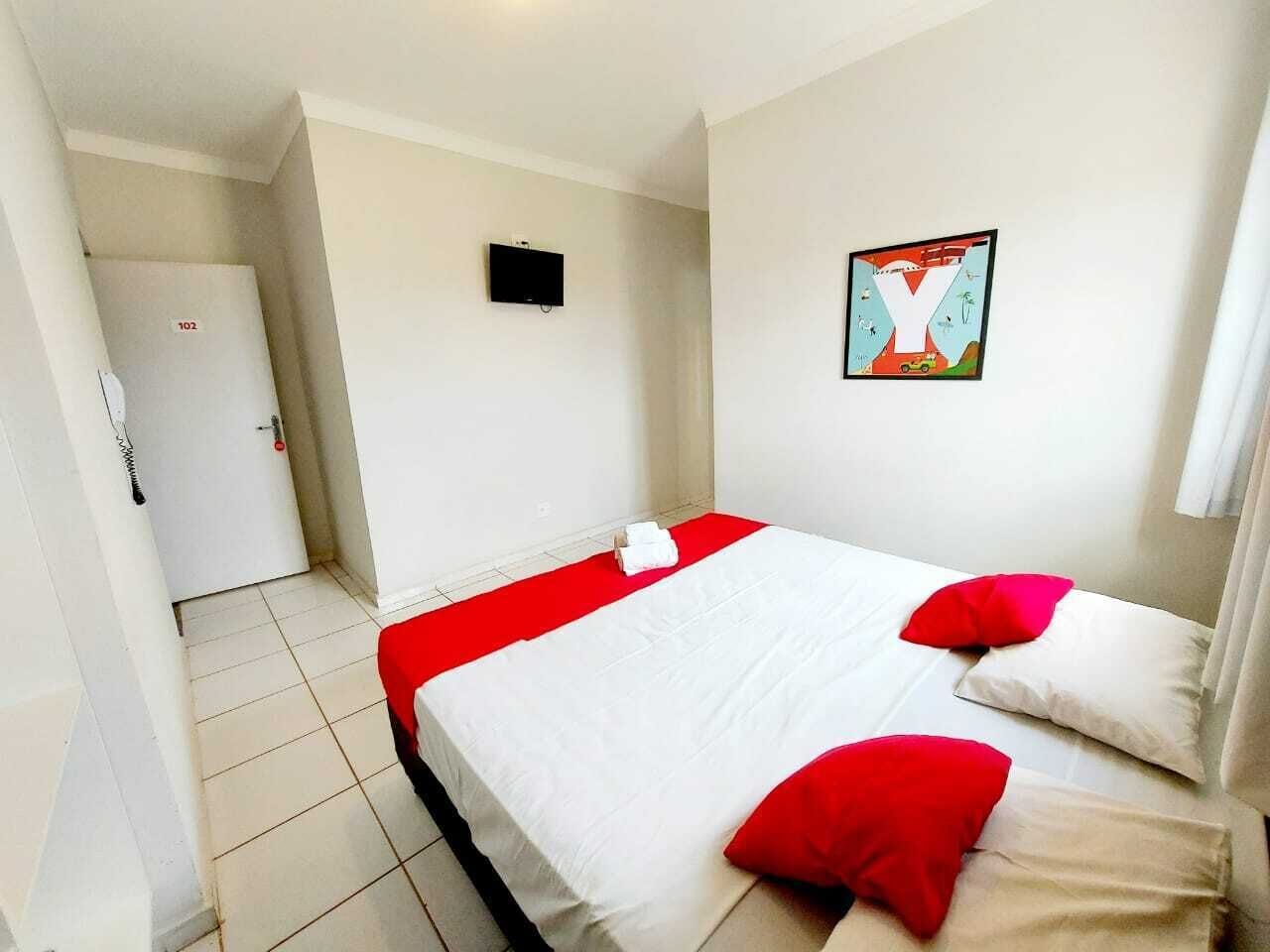Una habitación de hotel con una cama, televisión y puerta.