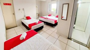 A hotel room with three beds, a bathroom, and a sliding glass door to the outside. - Hotel Jardim Do Cedro (Cedral)