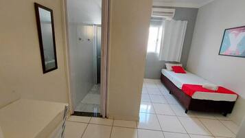 Una habitación de hotel con una cama, ducha y baño.