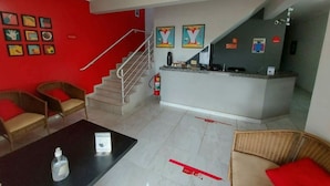 A hotel lobby with a red wall, a reception desk, a staircase, and a fire extinguisher. - Hotel Jardim Do Cedro (Cedral)