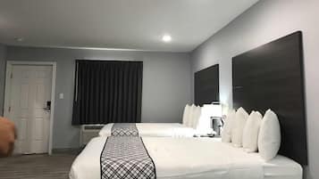 Habitació d'hotel amb dos llits, un mirall gran, una porta i una finestra amb cortines.