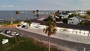 Un hotel frente a la playa con estacionamiento, palmeras y vistas al océano.