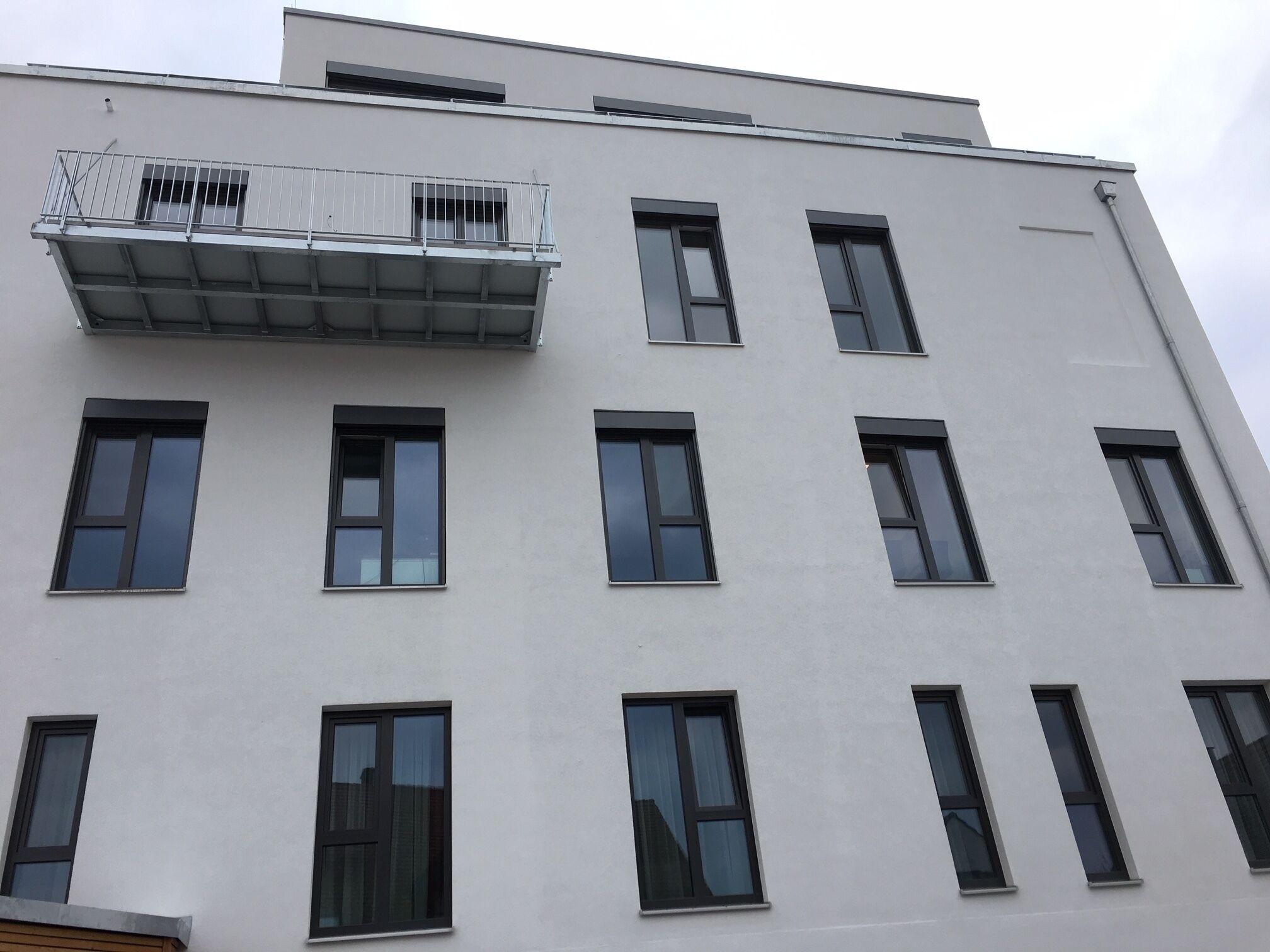 Un bâtiment moderne doté de nombreuses fenêtres et d’un balcon avec des garde-corps en métal.