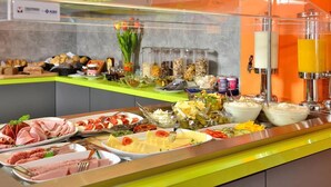 A buffet with various food items and a juice dispenser. - SleepySleepy Hotel Dillingen (Dillingen an der Donau)