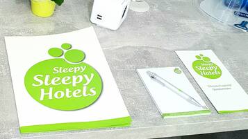 A desk with a brochure for Steepy Hotels, a small potted plant, a white device, and a water bottle.
