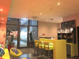 A modern bar area with yellow seating, a reception desk, and a menu board.