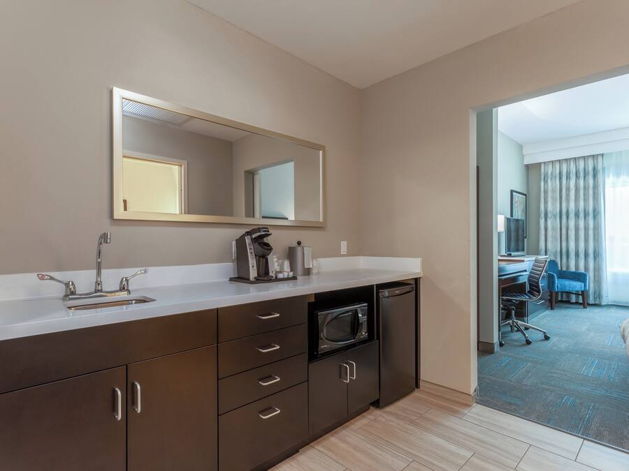 Une salle de bain d’hôtel moderne, équipée d’un lavabo, d’un miroir et d’un four à micro-ondes.