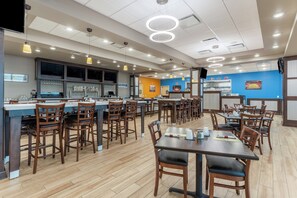 A restaurant with multiple dining tables and chairs, a bar area with a beer tap, and a blue accent wall with sports memorabilia. - Holiday Inn Hotel & Suites Jefferson City by IHG (Jefferson City)