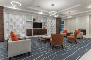 A modern lounge area with sofas, a coffee table, and a flat-screen TV. - Holiday Inn Hotel & Suites Jefferson City by IHG (Jefferson City)